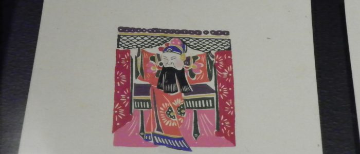 Imagen de artesanía de papel que representa a una figura de ópera tradicional sentada.