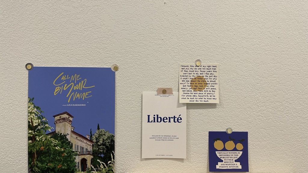 Fotografía de posters sobre Call me by your name en una pared. Paleta de colores azules, amarillos y blancos.