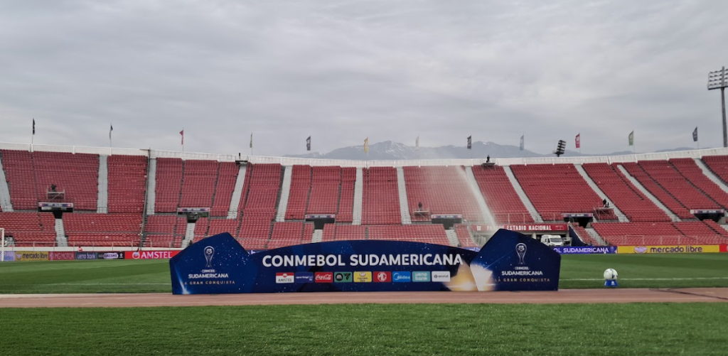 En esta imagen se muestra la cancha del Estadio Nacional y un cartel de la Copa Sudamericana.
