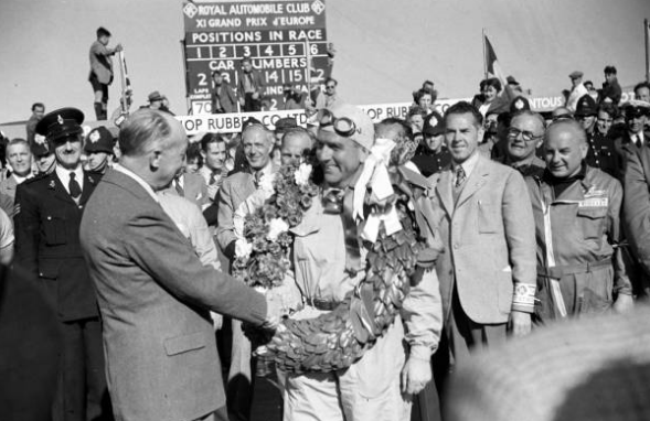 En la imagen se ve a Guiseppe Farina con la corona de laureles  como primer ganador del gran permio de gran bretaña en 1950.