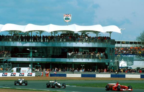 En la imagen se ven los autos del equipo mclaren y ferrari, y de fondo el remodelado paddock para el año 2000 en el circuito.
